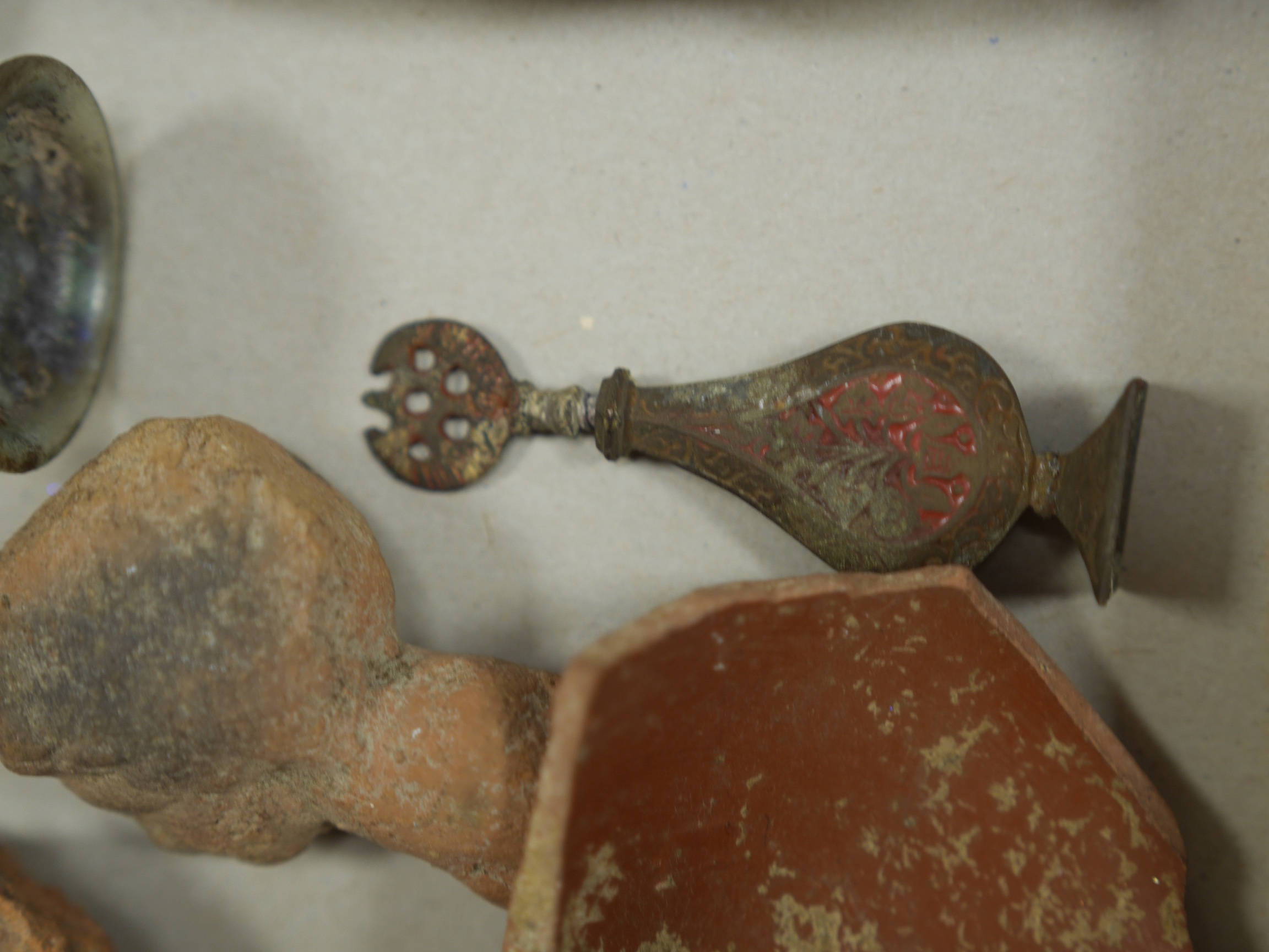 A collection of Roman, Ancient Greek and other items, including a glass vial, a broken glass bottle, a two handled pottery vase, shards of pottery items, a pottery figure head and other pottery items, an iron spear head,